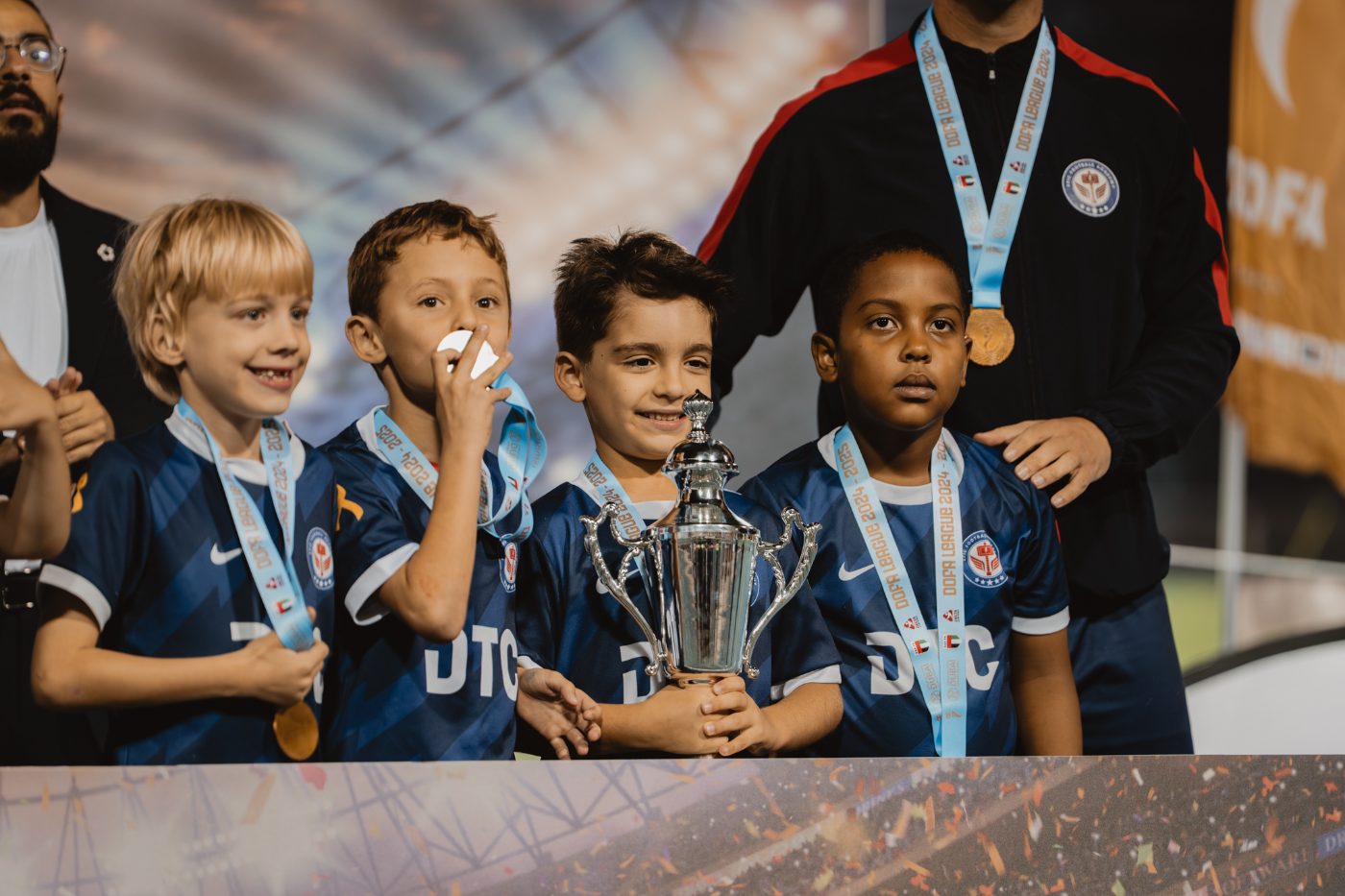 Young EPIC players celebrating on the podium with their medals and trophy